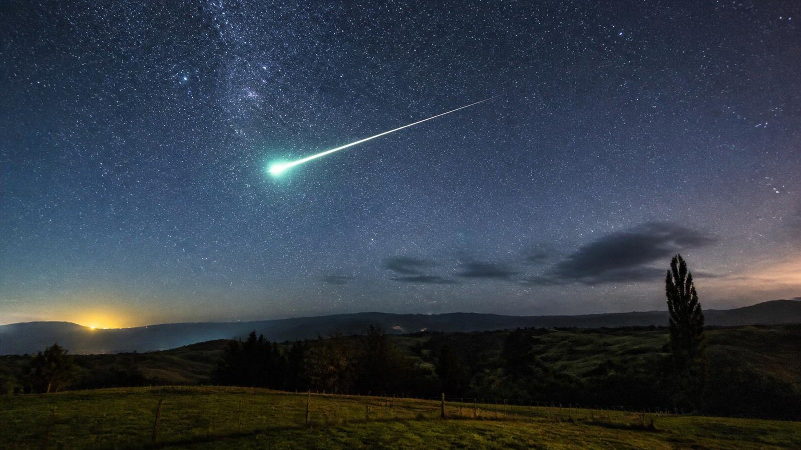 A fireball streaks across the night sky above rural New Zealand.
